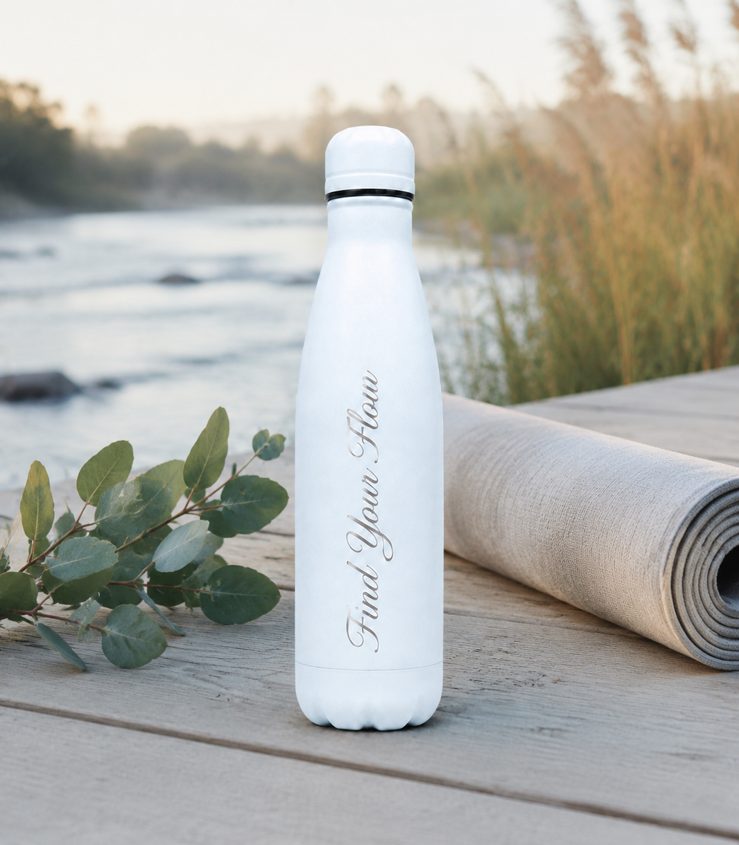 Sky Blue personalised stainless steel water bottle engraved “Find Your Flow” beside a yoga mat on a peaceful riverside deck