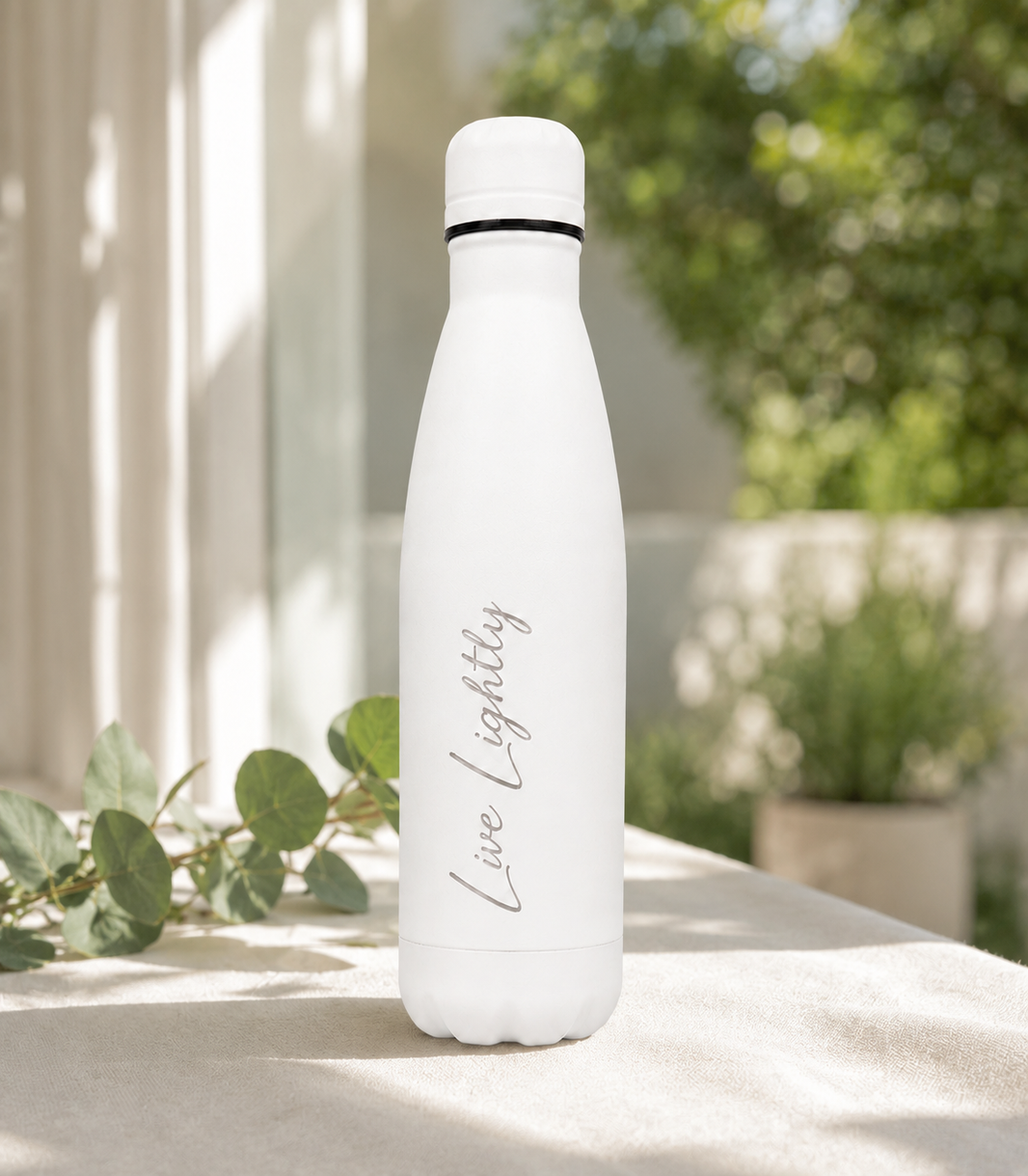 White 500ml personalised stainless steel water bottle engraved “Live Lightly” in a sunlit garden with greenery | Willys Bottles