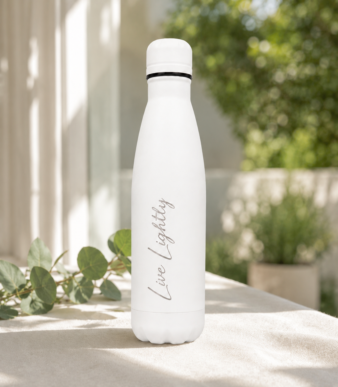 White 500ml personalised stainless steel water bottle engraved “Live Lightly” in a sunlit garden with greenery | Willys Bottles